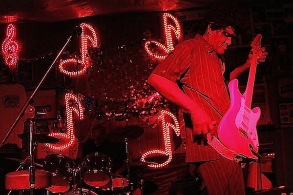 Guitarist performing under red neon lights