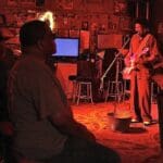 Man playing guitar on stage in a bar.