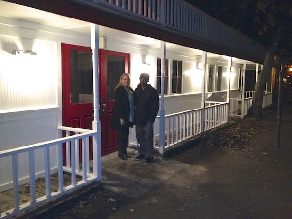 Couple standing outside a brightly lit building.