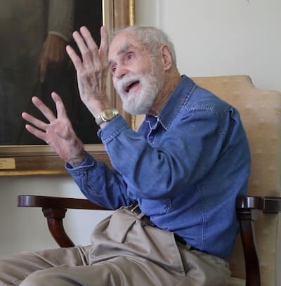 Man in denim shirt animatedly speaking