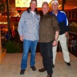 Three men standing together smiling for a photo.