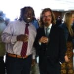 Two men in suits smiling at a party.