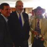 Three men in suits and hats at a party.