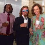 Three people smiling, holding drinks.
