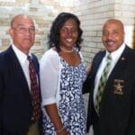 Three people in formal attire smiling.