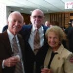 Two men and a woman smiling at a gathering.