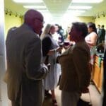 Man in suit talking to woman holding wine glass.