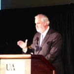 Man speaking at podium with microphone.