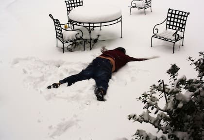 Individual making snow angel in backyard