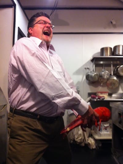 Man playfully holding lobster in kitchen