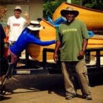 Three people loading a canoe on a trailer.