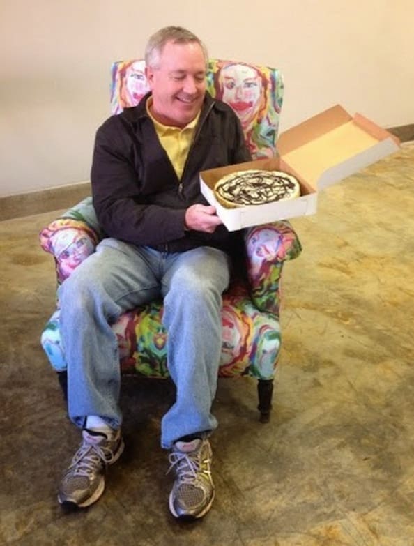 Person enjoying cake in patterned chair.