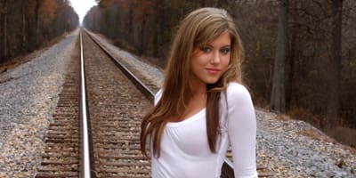 Woman in white shirt near train tracks