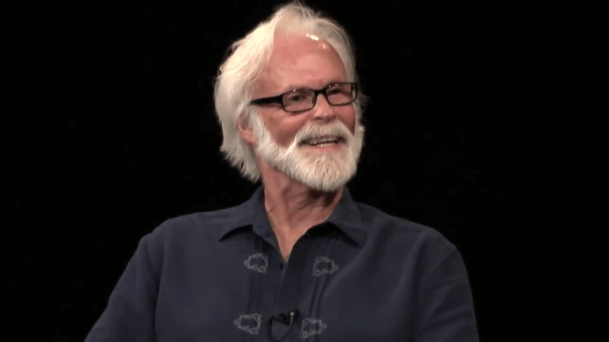 Bearded man smiling against black background
