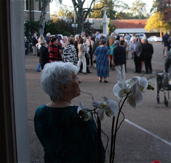 Elderly woman near orchid plant