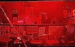 Red lit bar with people sitting at tables.