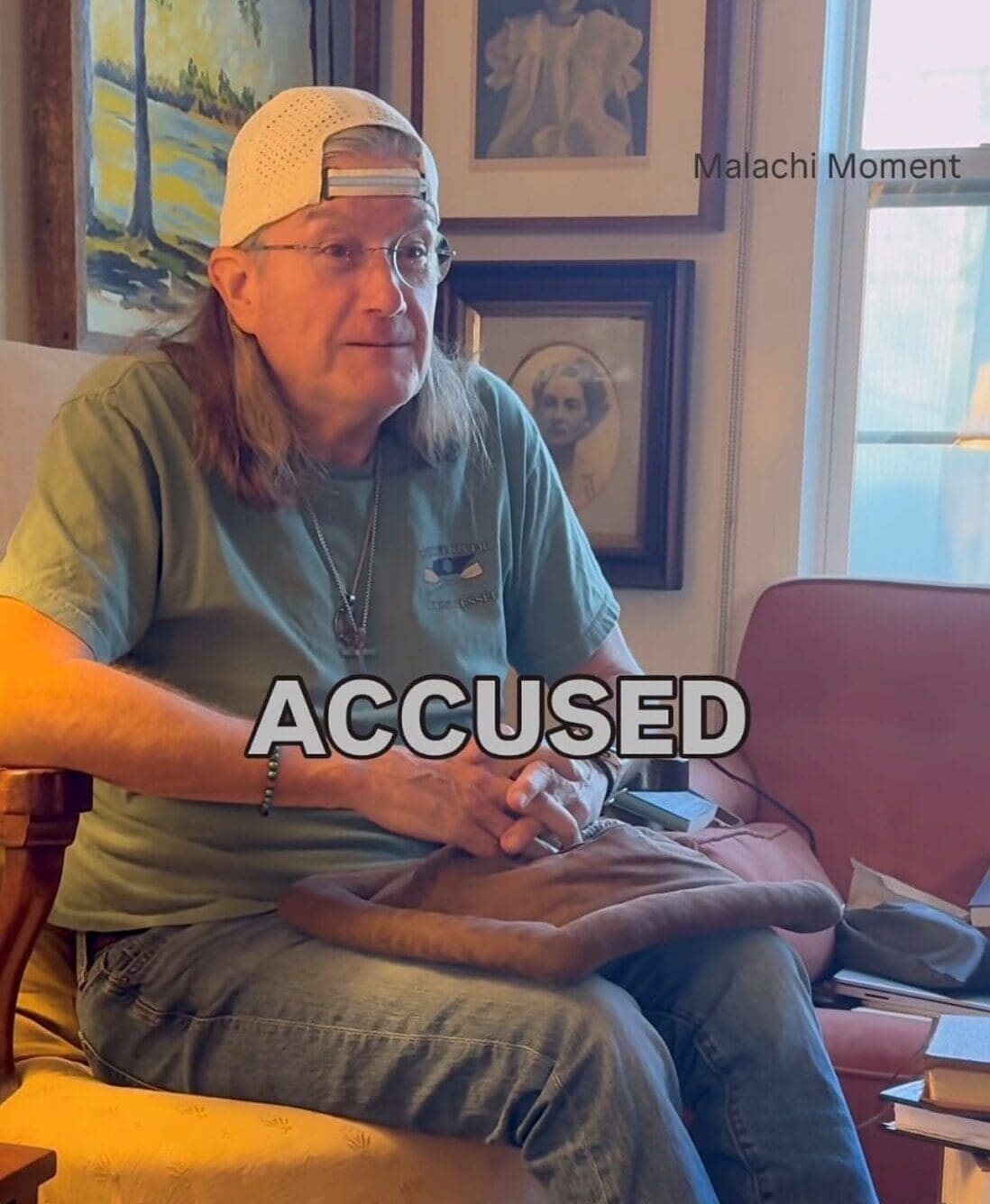 Man wearing backward cap sitting, “ACCUSED” overlay