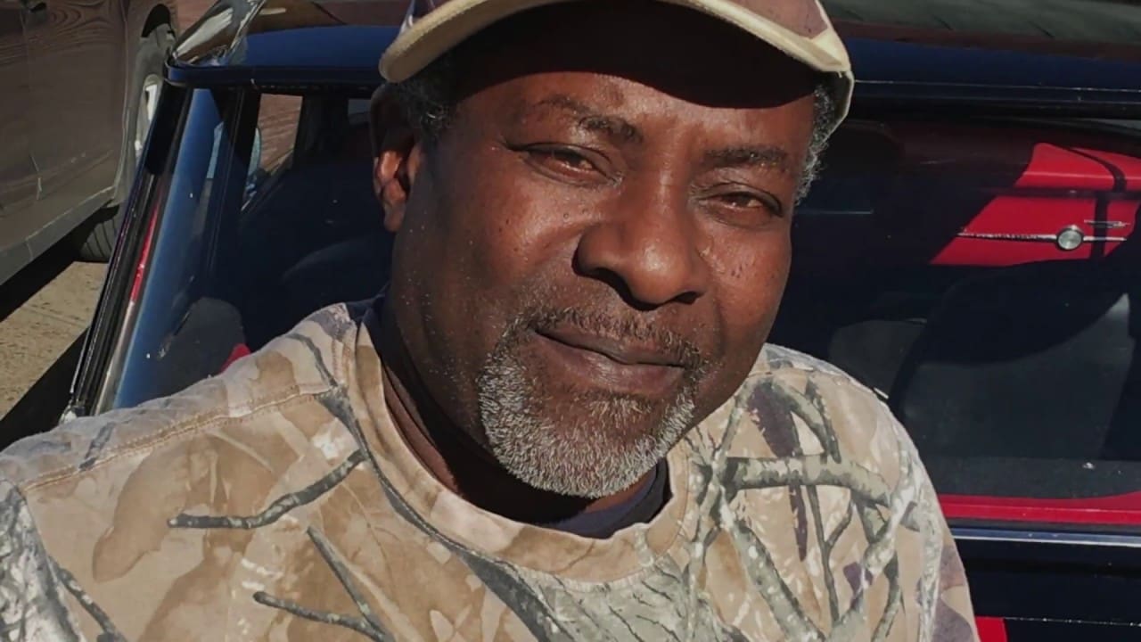 Smiling man wearing camouflage shirt and cap