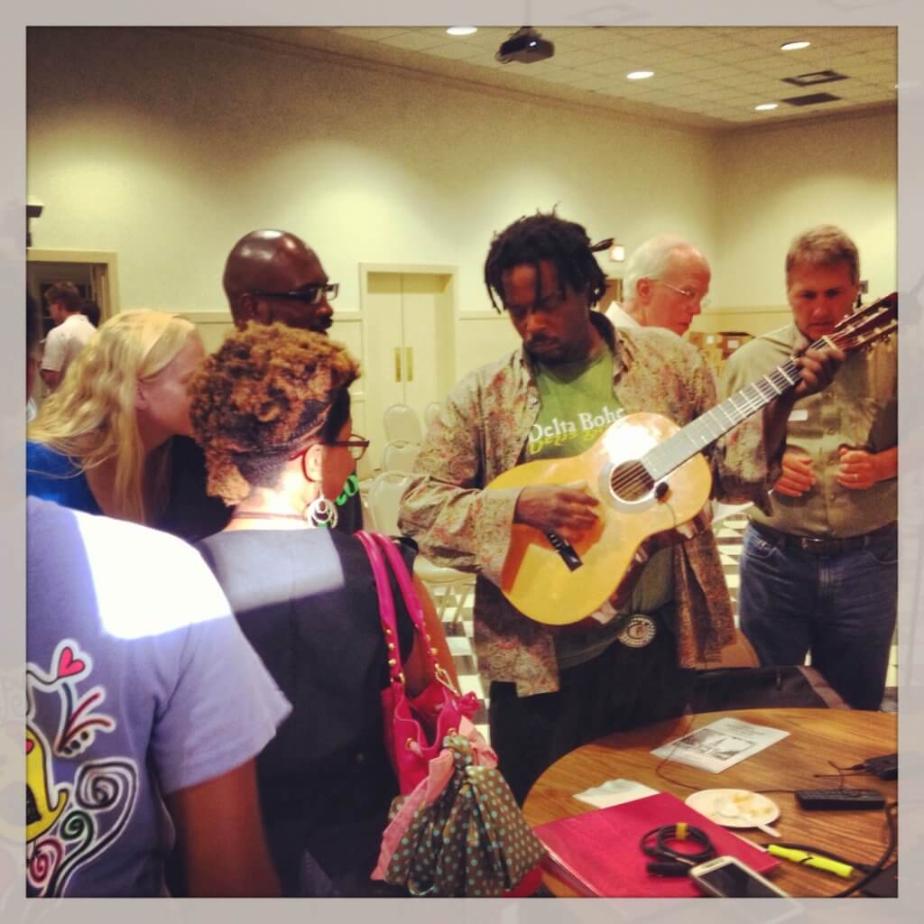 Man playing guitar surrounded by attentive listeners
