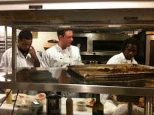 Three chefs working in busy restaurant kitchen