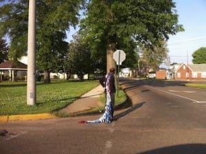 Person dragging long blue cloth on sidewalk
