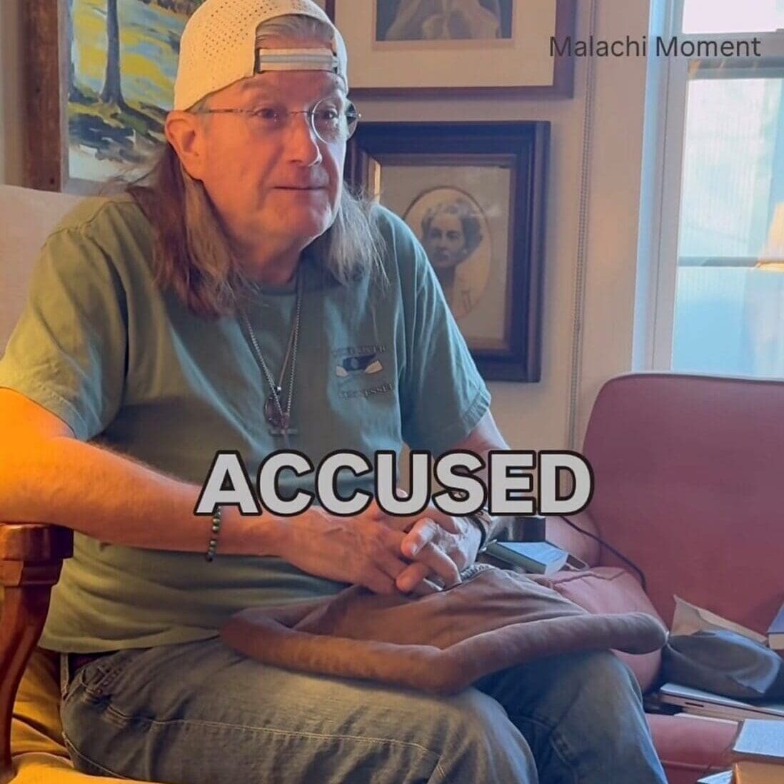 Man wearing backward cap sitting, “ACCUSED” overlay