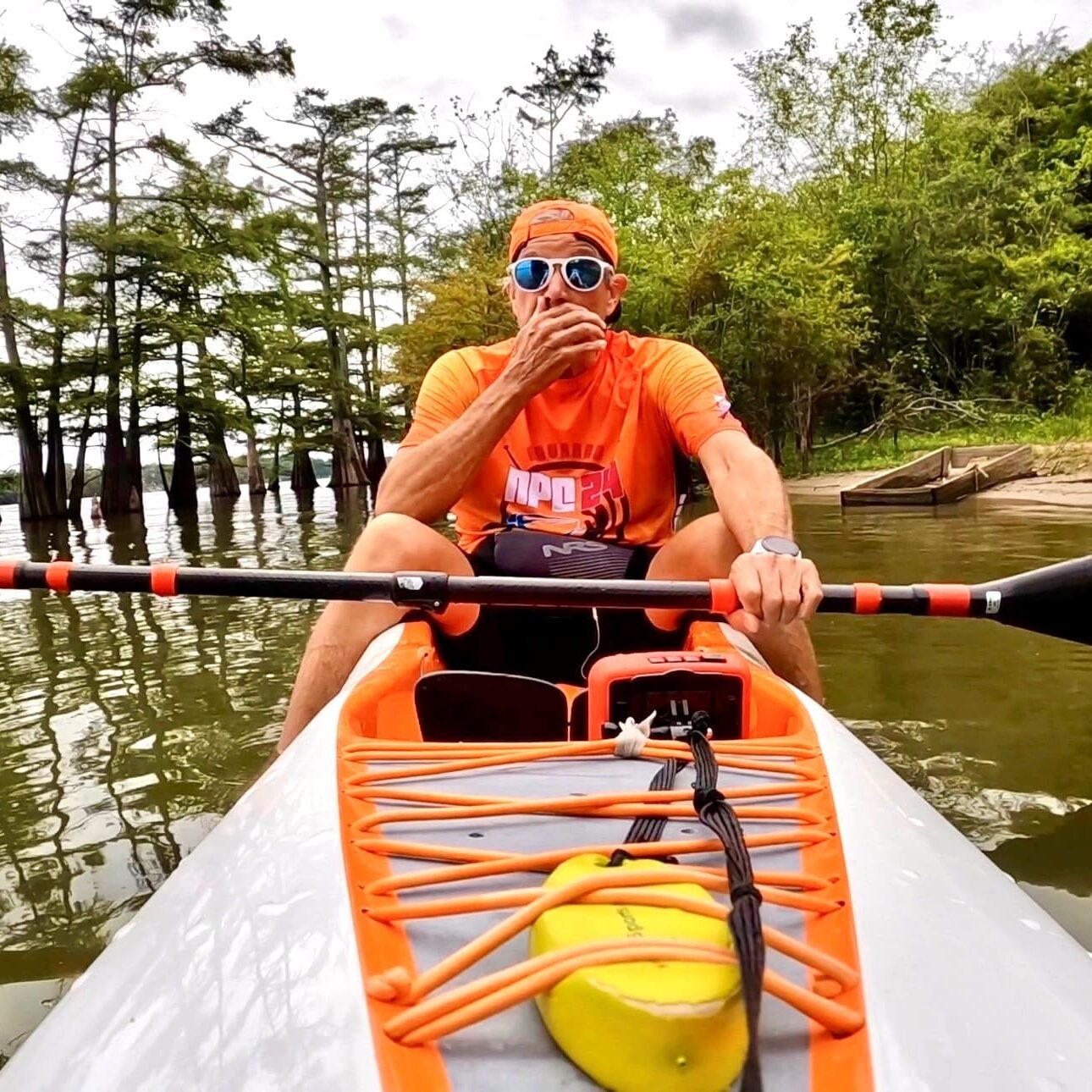 Person in orange kayaking on tranquil lake