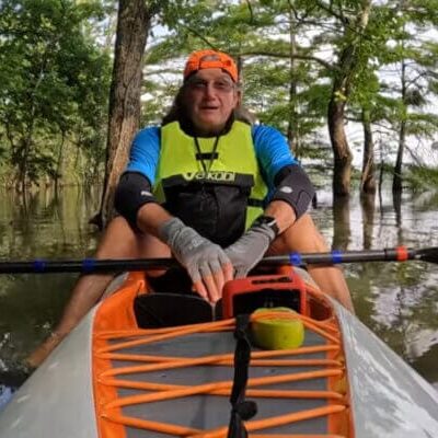 Man kayaking through forested waterway